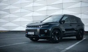 Czarny SsangYong Torres z czarnymi felgami stoi na parkingu przed nowoczesnym budynkiem o geometrycznej fasadzie.