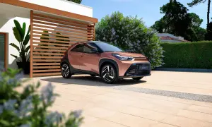 Różowy Toyota Aygo X na podjeździe przed nowoczesnym domem. Sprawdź atrakcyjną toyota aygo x cena!