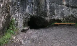 Wejście do jaskini w skale, obok ławka i kamienna ława. Tajemnicza dziura w górach, może w okolicach Zakopanego.