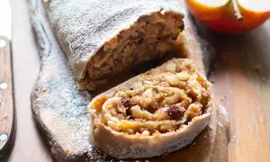 Strudel di mele con pasta sfoglia, cosparso di zucchero a velo, su tagliere di legno.