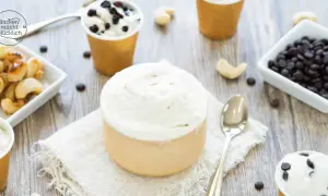 Cremiges Vanilleeis ohne Ei, serviert in Bechern, mit Cashews und Schokodrops daneben.