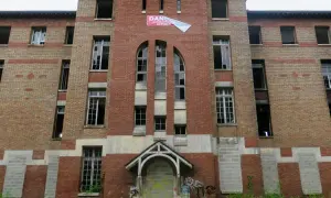 Façade imposante de l'hôpital abandonné d'Angicourt, avec ses fenêtres brisées et un panneau "DANGER ACCÈS INTERDIT AU PUBLIC".