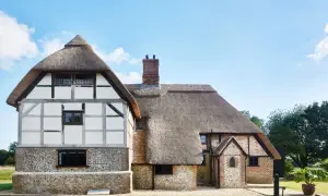 Ein mittelalterliches Bauernhaus mit Strohdach und Fachwerk.