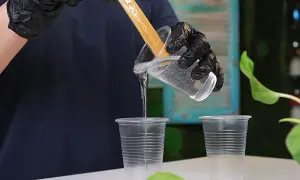Mani guantate versano resina epossidica trasparente in un bicchiere, un passaggio cruciale per il tempo indurimento resina epossidica.