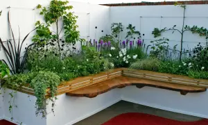 Moderne hochbeet ideen mit integrierter Holzbank und üppiger Bepflanzung in Weiß und Lila.
