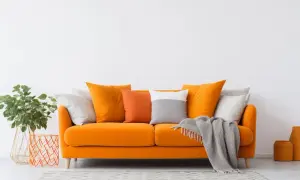 Divano arancione acceso, un'ispirazione per come scegliere il colore del divano. Cuscini colorati e coperta grigia completano l'arredo.