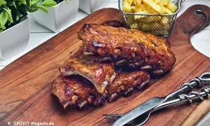 Saftige, geschmorte Rippchen mit knusprigen Pommes Frites auf einem Holzbrett, bereit zum Genießen.