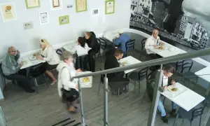 Wnętrze baru turysta. Ludzie jedzą przy stolikach, jeden z nich niesie tacę z jedzeniem.