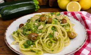 Un piatto invitante di pasta con zucchine e tonno, condita con olive e un tocco di limone.