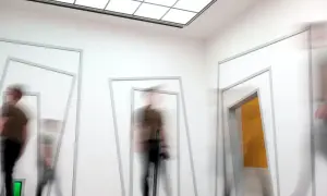 Mensen bewegen door een gang met geometrische openingen, wat een indruk geeft van een sensorische informatieverwerking test.