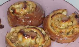 Saftige Apfelschnecken mit Glasur, ein köstliches Rezept für süße Momente. Daneben liegen ein paar Rosinen.