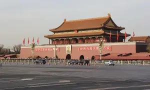 Brama **Tiananmen** w Pekinie, z portretem Mao i chińskimi napisami. Tłumy ludzi i samochody na placu.