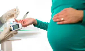 Gravid kvinna genomgår glukosbelastning. En hand med handske tar blodprov från fingret för att mäta blodsockret.