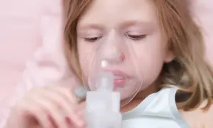 Dziewczynka z maską inhalatora na twarzy.
