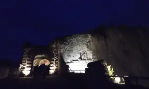Nuit tombante sur un château abandonné dans la Somme. Des lumières éclairent l'entrée voûtée et les vieilles pierres.