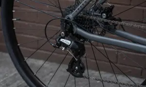 Tylna przerzutka Shimano Altus z widocznym hakiem do przerzutki, kasetą i łańcuchem na rowerze.