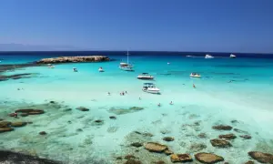 Piękne cypr plaże z turkusową wodą, łodziami i ludźmi kąpiącymi się w morzu.