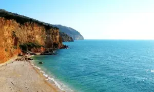 Spiaggia Punta Rossa: scogliere dorate si tuffano nel mare turchese, un angolo di paradiso incontaminato.