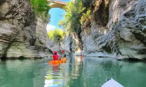 Kayak tra imponenti pareti rocciose, simili a **marmitte dei giganti**, sotto un antico ponte.