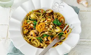 Leckere Spaghetti-Rezepte mit Pilzen, Karottenstreifen und Spinat, garniert mit Nüssen.