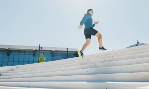 Un homme court sur des escaliers extérieurs. Est-ce que courir fait maigrir ? Oui, l'effort physique comme celui-ci aide à brûler des calories.