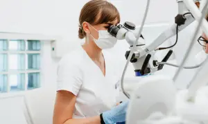Dentystka bada zęby pod mikroskopem. Nieleczona próchnica może prowadzić do poważnych problemów.