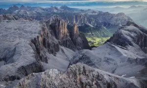 Majestätische Felsformationen am Piz Boe, mit einem grünen Tal und Häusern in der Ferne.