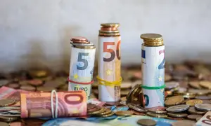 Zrolowane banknoty euro (5, 10, 50) z monetami na górze i wokół. To może być zgłoszenie darowizny od rodziców.