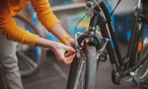 Osoba w żółtej bluzie dokonuje wymiany klocków hamulcowych w rowerze, dbając o bezpieczeństwo jazdy.