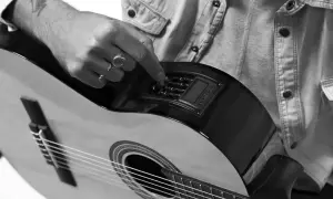 Dłoń z pierścionkami reguluje pokrętła na gitarze, przygotowując się do nauki gry na gitarze elektrycznej.
