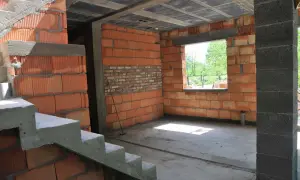 Wnętrze w budowie, widoczne schody i ściany z pustaków ceramicznych. Trwa samowolne przekształcenie budynku gospodarczego na mieszkalny.
