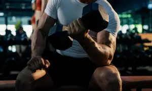 Mężczyzna ćwiczy biceps na wyciągu, napinając mięśnie podczas podnoszenia ciężaru.