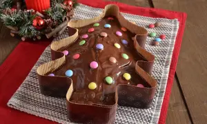 Dolce a forma di albero di Natale ricoperto di glassa al cioccolato e decorato con caramelle colorate.