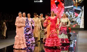 Modelos desfilan en la **pasarela SIMOF** con trajes de flamenca vibrantes y volantes.