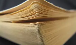 Zbliżenie na strony starej, pożółkłej książki, widoczne krawędzie kartek.