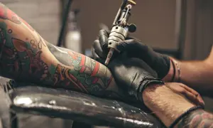 Un artista de **london tattoo** trabaja en un brazo con un diseño colorido.