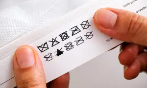 Etichetta con simboli di lavaggio e asciugatura, utili per capire le classi energetiche asciugatrici e la composizione del tessuto (100% poliestere).