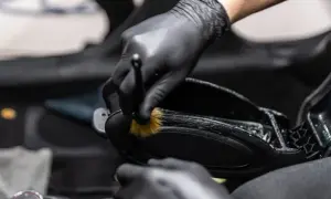 Rękawiczki i pędzelek detailingowy precyzyjnie czyszczą zakamarki konsoli środkowej samochodu.