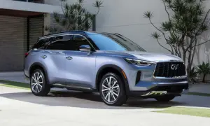 Elegancki, srebrny Infiniti QX60 parkuje przed nowoczesnym domem, otoczony bujną zielenią.