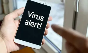 Dłoń trzyma smartfon z napisem "Virus alert!". Szukasz najlepszego darmowego antywirusa na Androida, by uniknąć takich komunikatów.