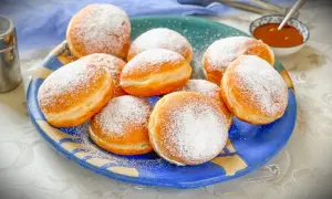 Ein Teller voller frisch gebackener Krapfen, bestäubt mit Puderzucker. Dieses Krapfen Rezept ist ein Genuss!