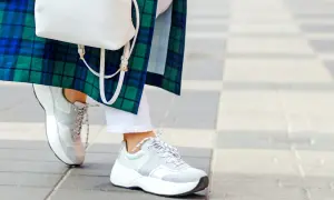 Stylowe białe sneakersy damskie idealnie komponują się z białą stylizacją i zielono-niebieską kraciastą marynarką.