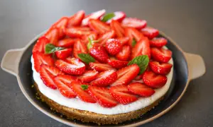 Tarte aux fraises mascarpone, une gourmandise estivale recouverte de fruits rouges frais et de feuilles de menthe.
