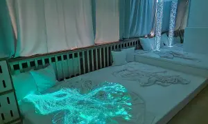 Ein beruhigender Snoezelen Raum mit weißen Matratzen, Kissen und faszinierenden Lichteffekten, darunter leuchtende Glasfasern.