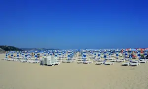 Plaża w Albena Bułgaria, rzędy leżaków i parasoli w niebiesko-białe pasy pod błękitnym niebem.