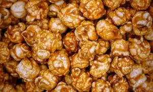 Gros plan sur une montagne de pop-corn caramel, chaque grain enrobé d'une sauce dorée et brillante. Un délice croustillant et sucré.