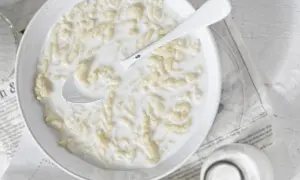 Miseczka pełna pysznych klusek lanych na mleku, z łyżką gotową do pierwszego kęsa.