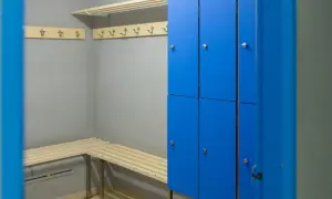 Un vestiaire avec des casiers bleus, des bancs en bois et des patères.