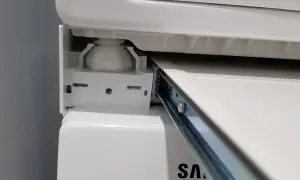 Zbliżenie na mechanizm łącznika suszarki na pralce Samsung, widoczny metalowy wspornik i biała podstawa.