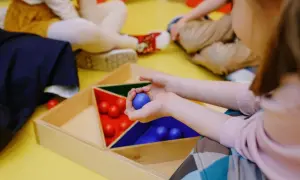Dzieci ćwiczą trening uwagi, sortując kolorowe kulki w drewnianej ramce.
